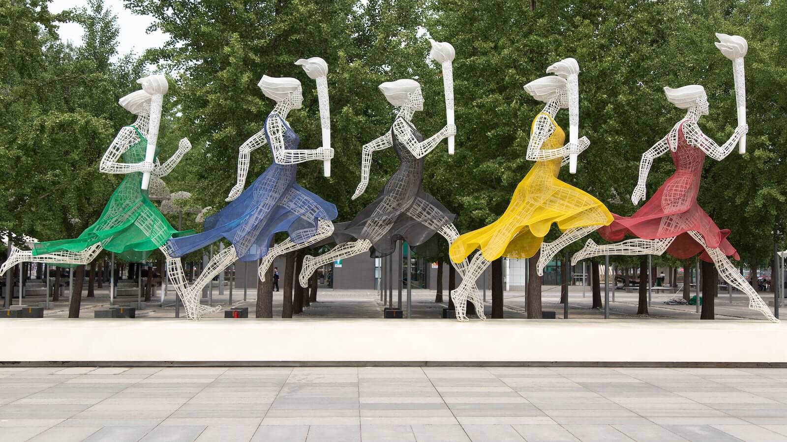 Eine Skulptur von fünf Personen, die die olympischen Ringe tragen