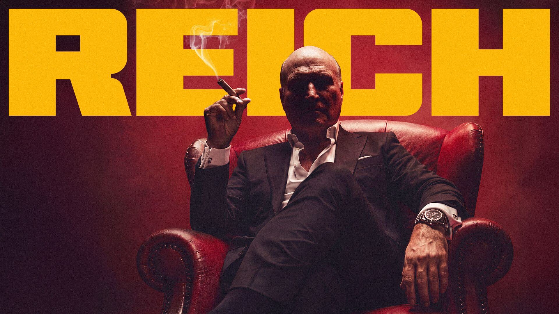 Ein älterer Mann mit Glatze sitzt auf einem roten, ledernen Armsessel. Sein Gesicht ist in Schatten gehüllt. Darüber der Titel des Podcasts 'REICH'