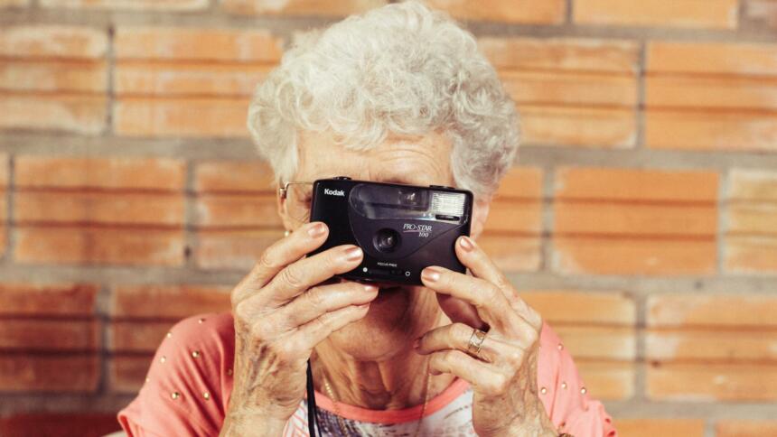 Eine ältere Frau, mit einer Kamera vor dem Gesicht