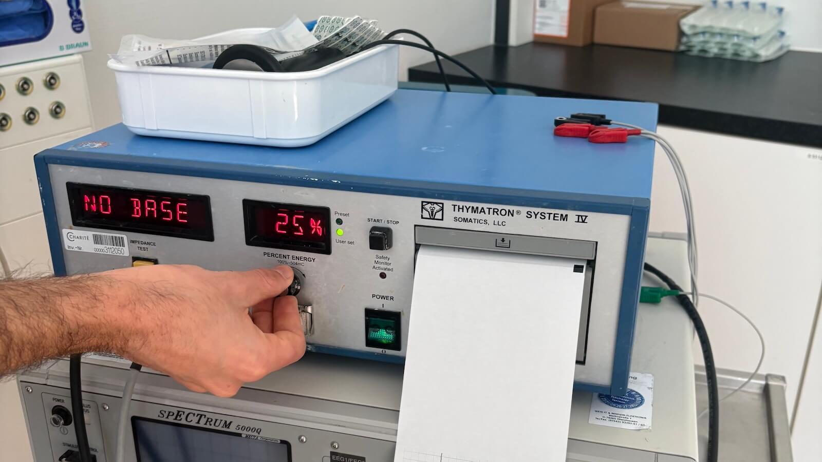Ein elektrisches Gerät mit einer analogen Anzeige und ein paar Reglern. Eine Hand, die einen der Regler betätigt.