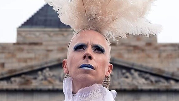 Drag-Queen Olympia Bukkais vor dem Brandenburger Tor mit Federschmuck auf dem Kopf